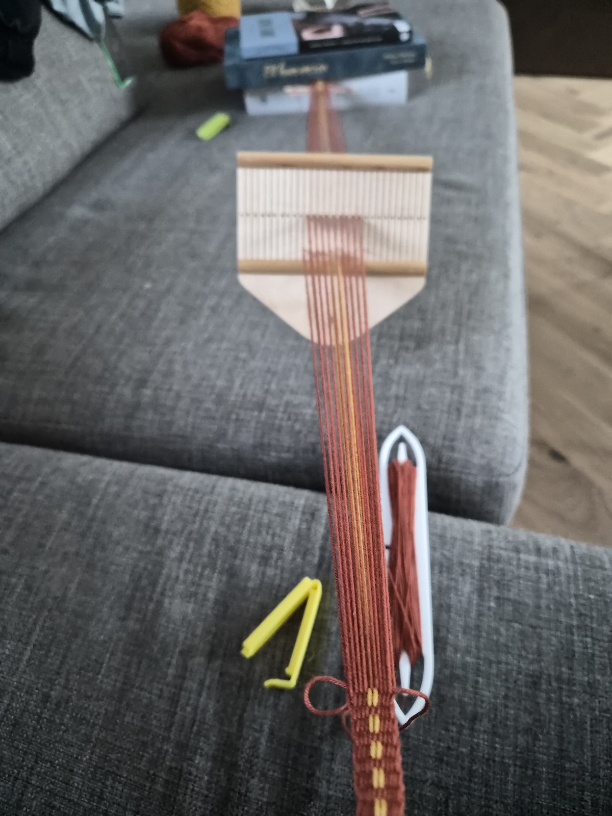 A band being woven on a rigid heddle, showing several tools