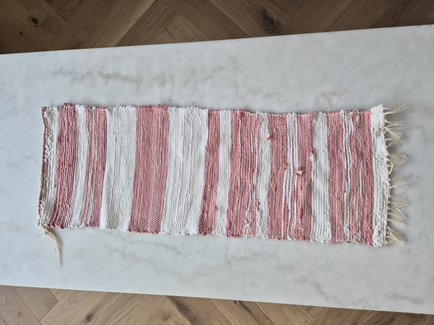 A table runner looking like a little rag rug on a marble table
