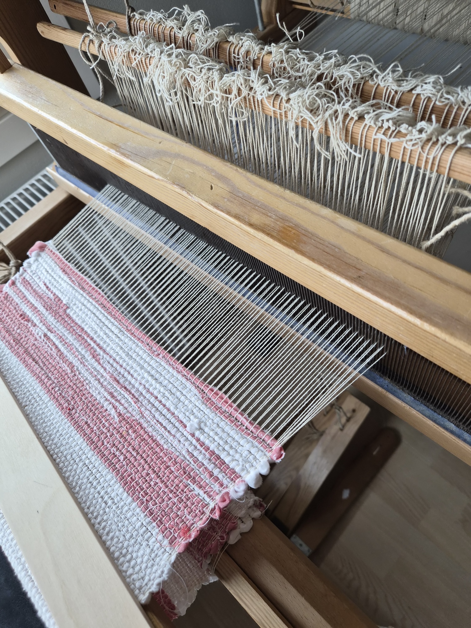 A table mounted loom in the middle of weaving a runner
